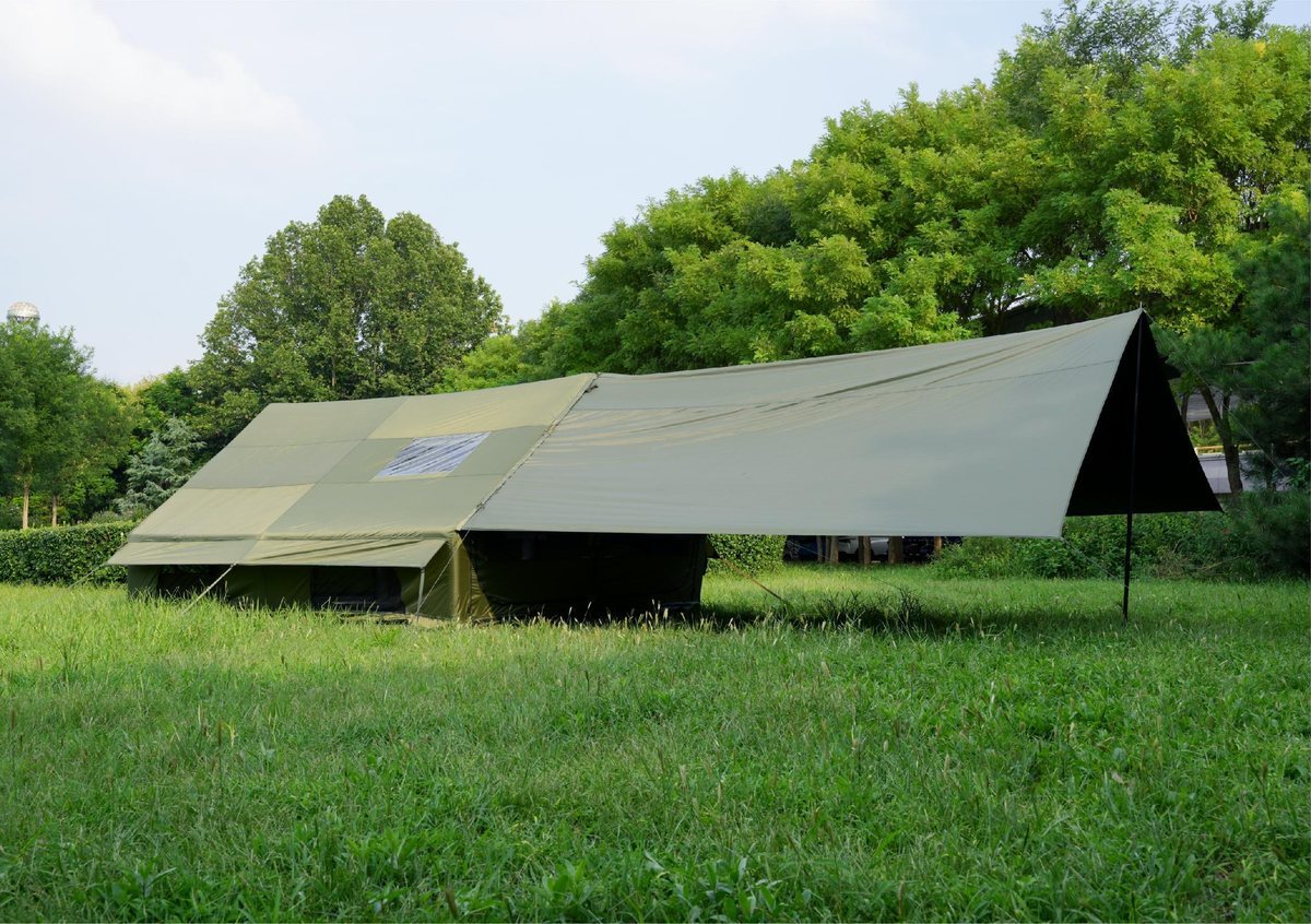 Grüne und khakifarbene Luftzelte mit Vordach an einem Campingplatz am Fluss